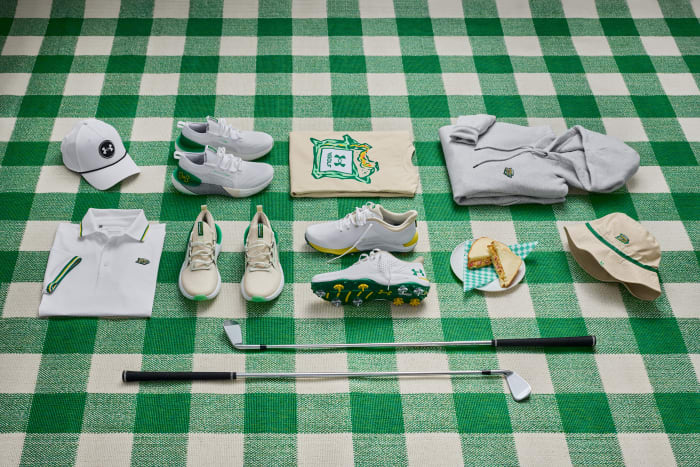 Under Armour apparel and shoes on a green blanket.